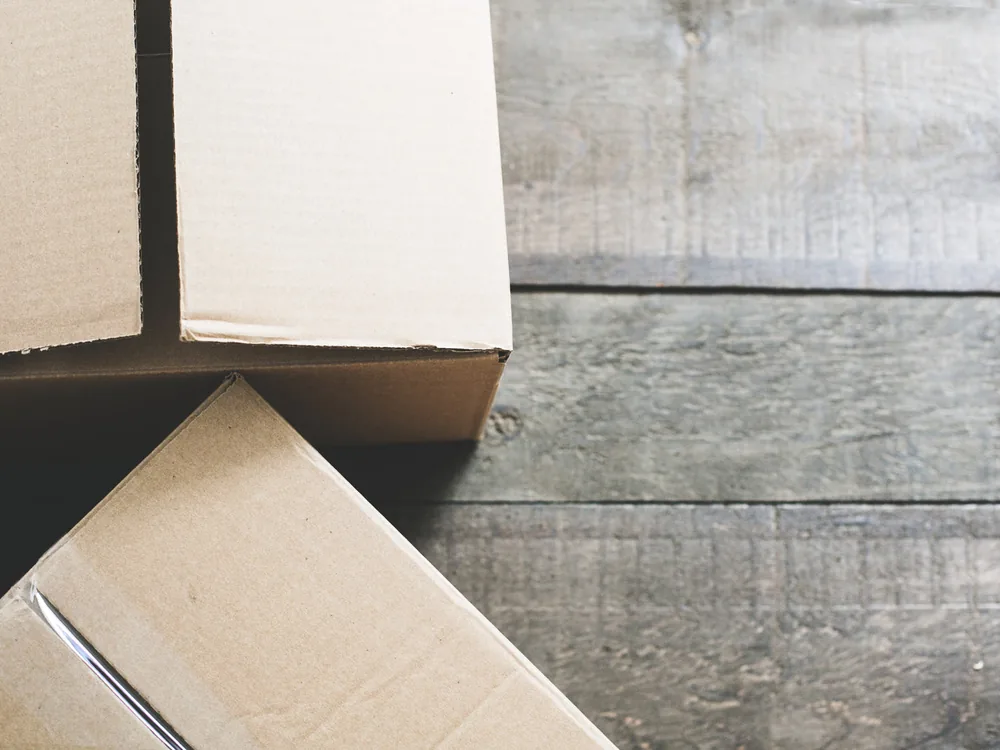Cardboard shipping boxes of Bali jewelry ready for export on a wooden floor