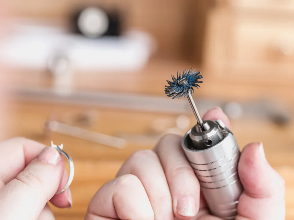 Artisan’s hands finishing a handmade silver ring with a rotary polishing tool
